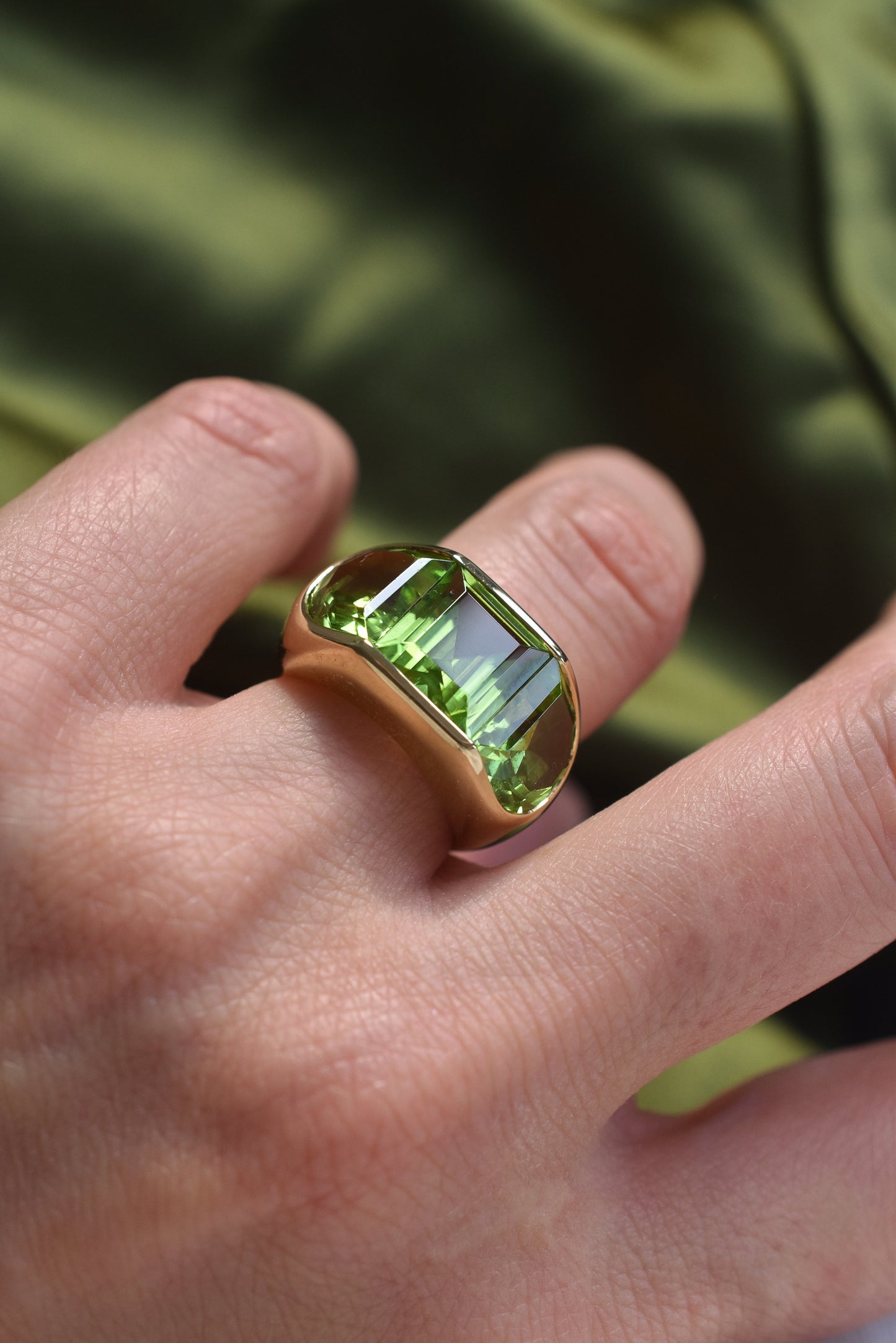A Large Channel-set Peridot and 18K Gold Trilogy Ring