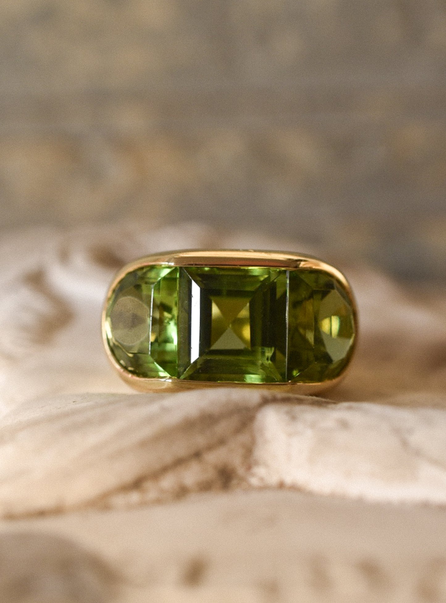 A Large Channel-set Peridot and 18K Gold Trilogy Ring