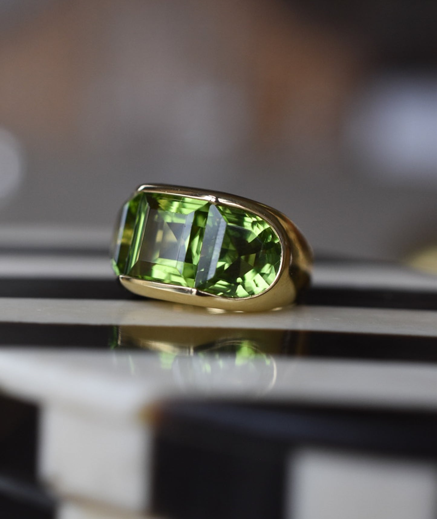 A Large Channel-set Peridot and 18K Gold Trilogy Ring