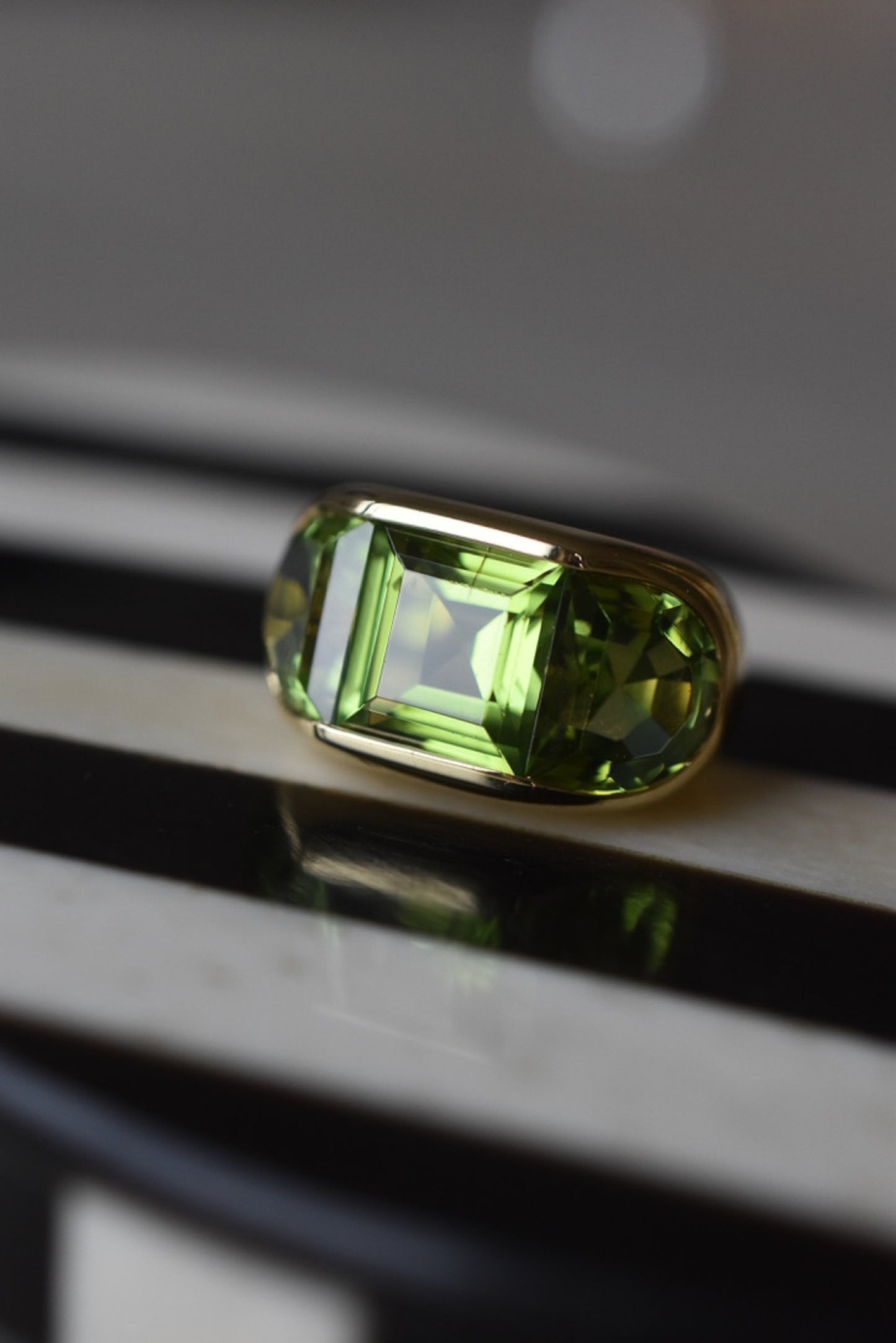 A Large Channel-set Peridot and 18K Gold Trilogy Ring