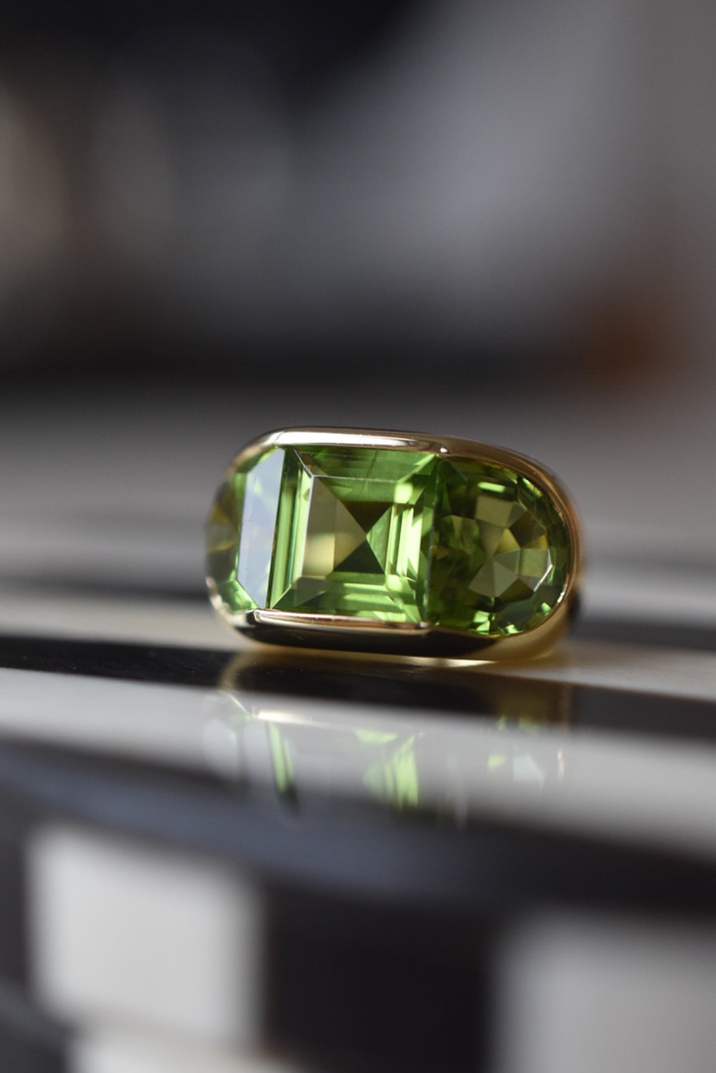 A Large Channel-set Peridot and 18K Gold Trilogy Ring