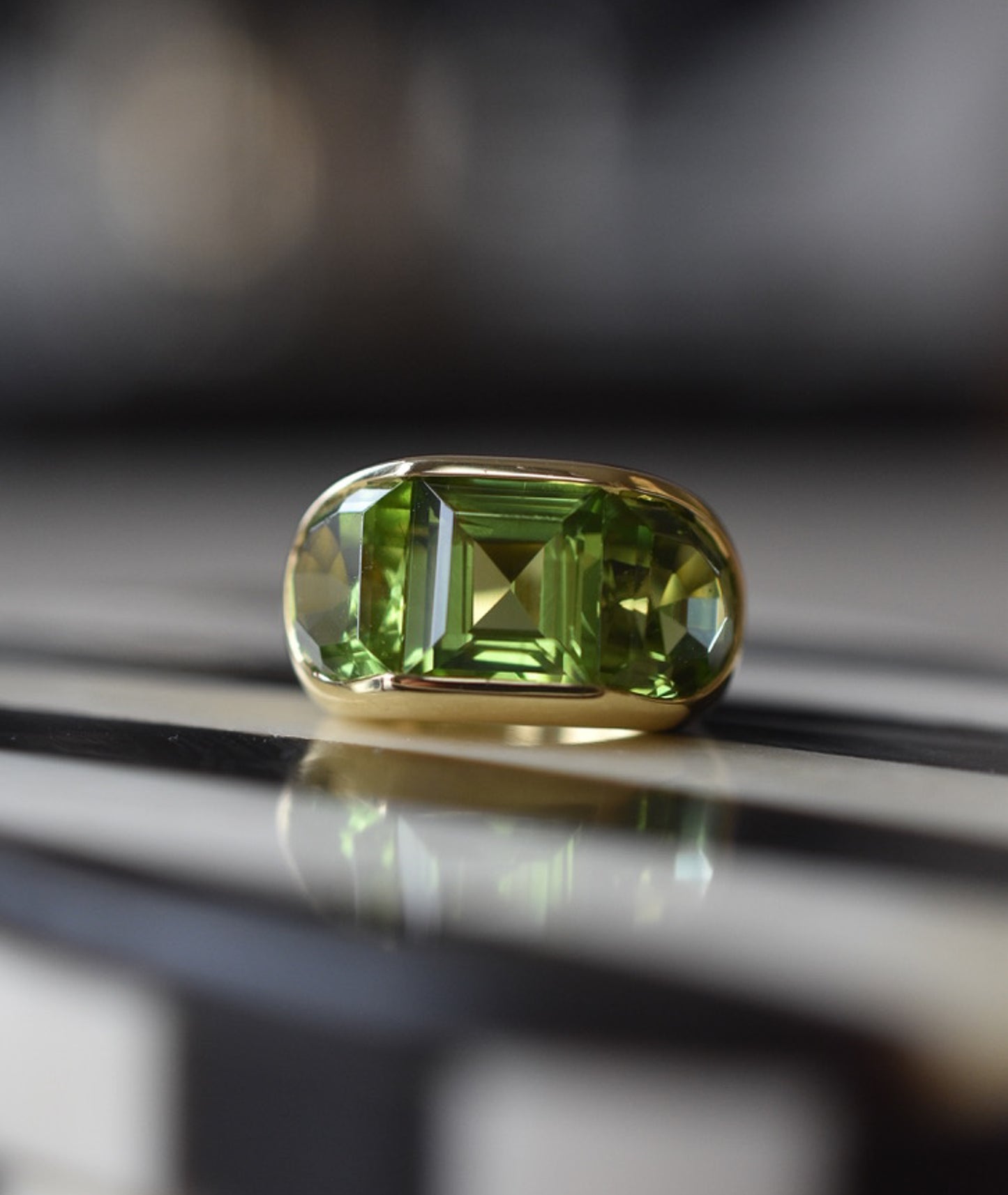 A Large Channel-set Peridot and 18K Gold Trilogy Ring