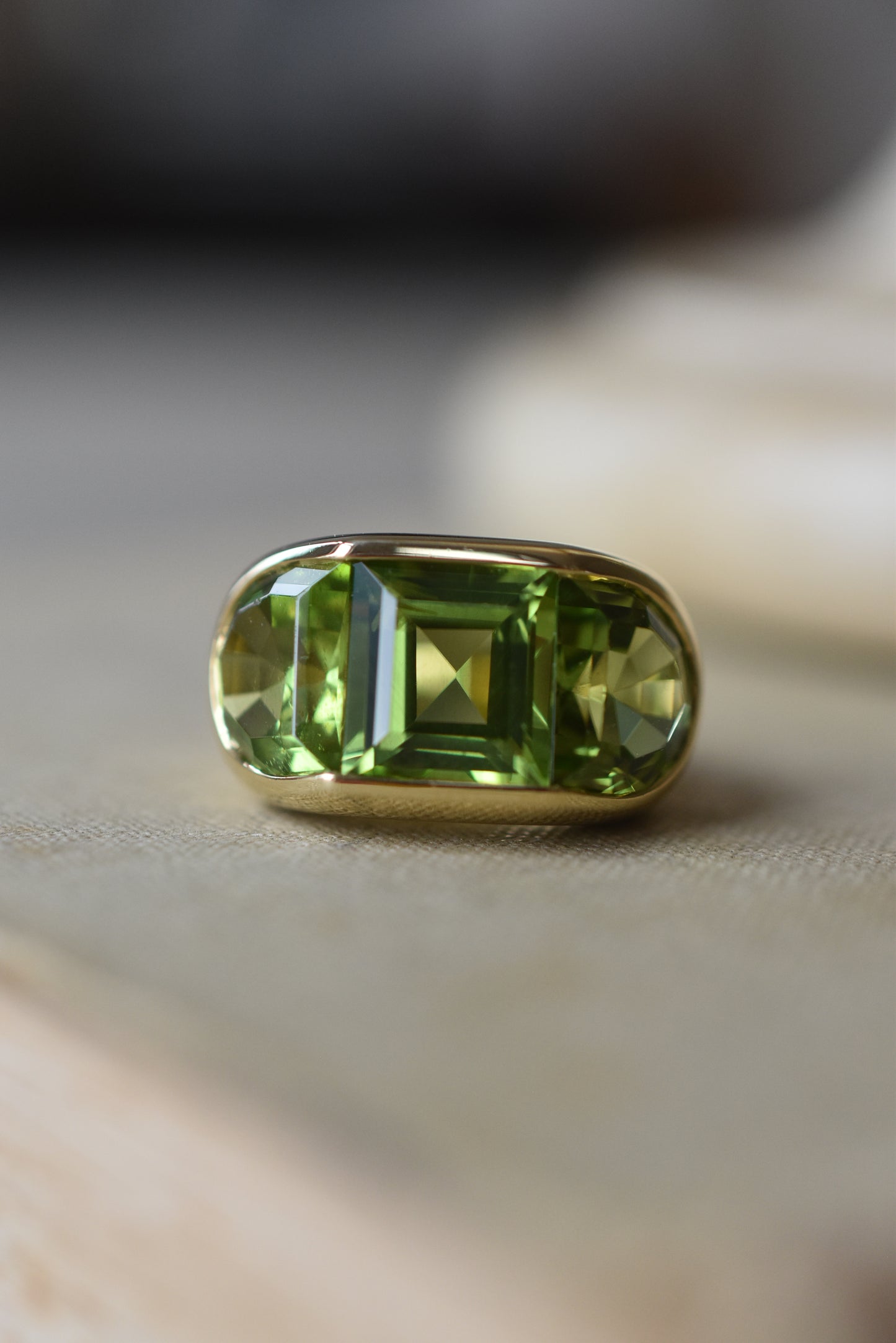 A Large Channel-set Peridot and 18K Gold Trilogy Ring