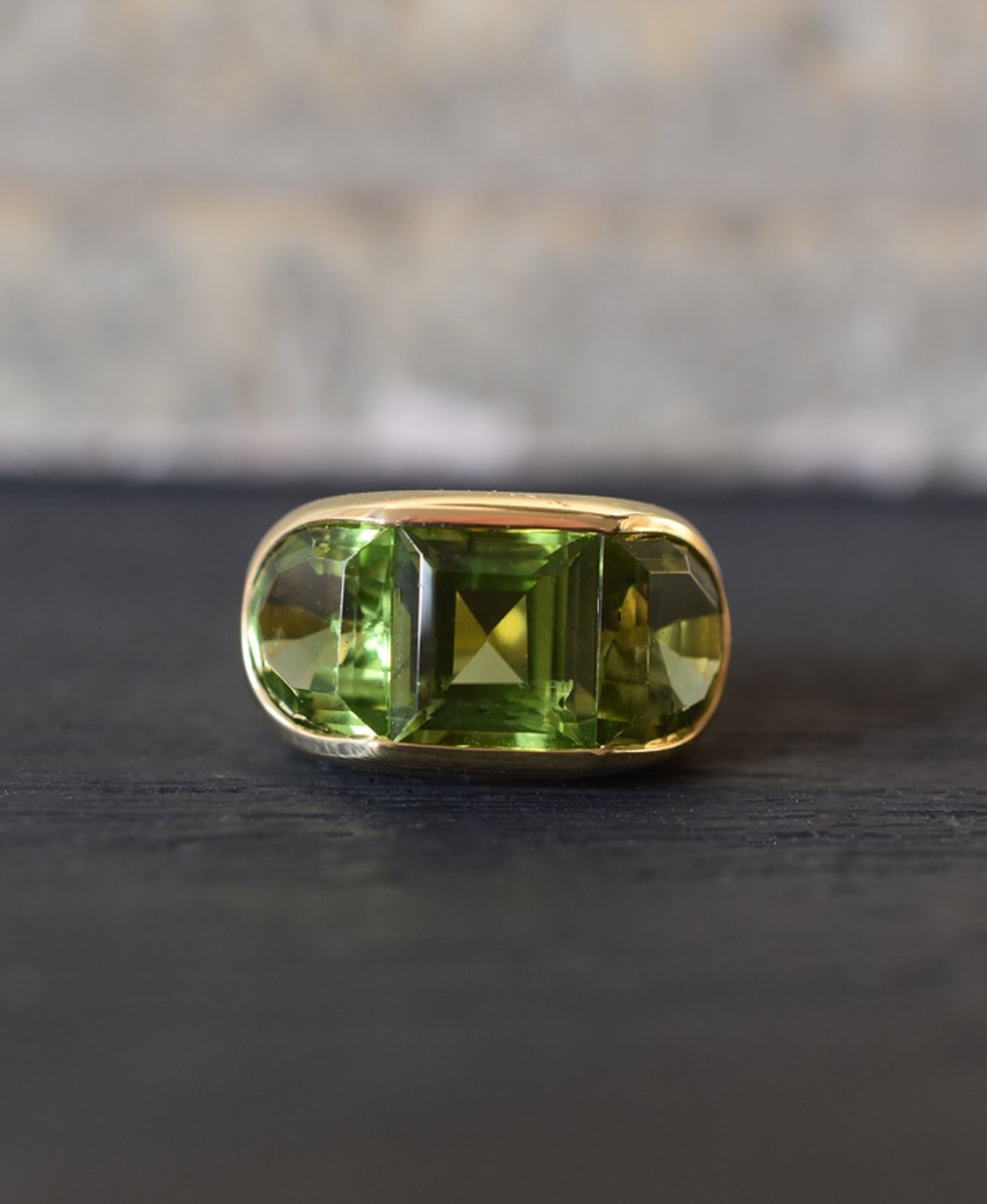 A Large Channel-set Peridot and 18K Gold Trilogy Ring