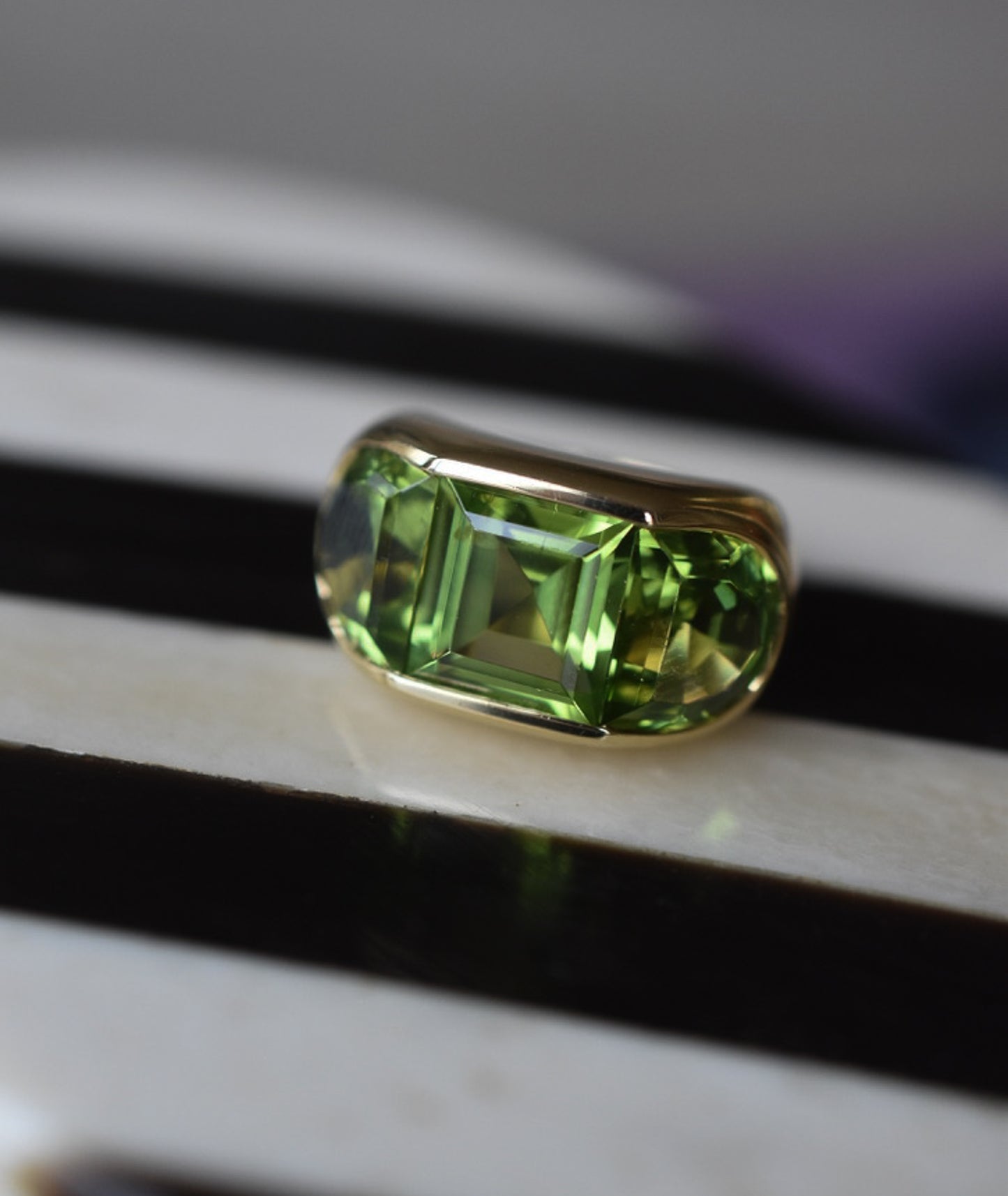 A Large Channel-set Peridot and 18K Gold Trilogy Ring