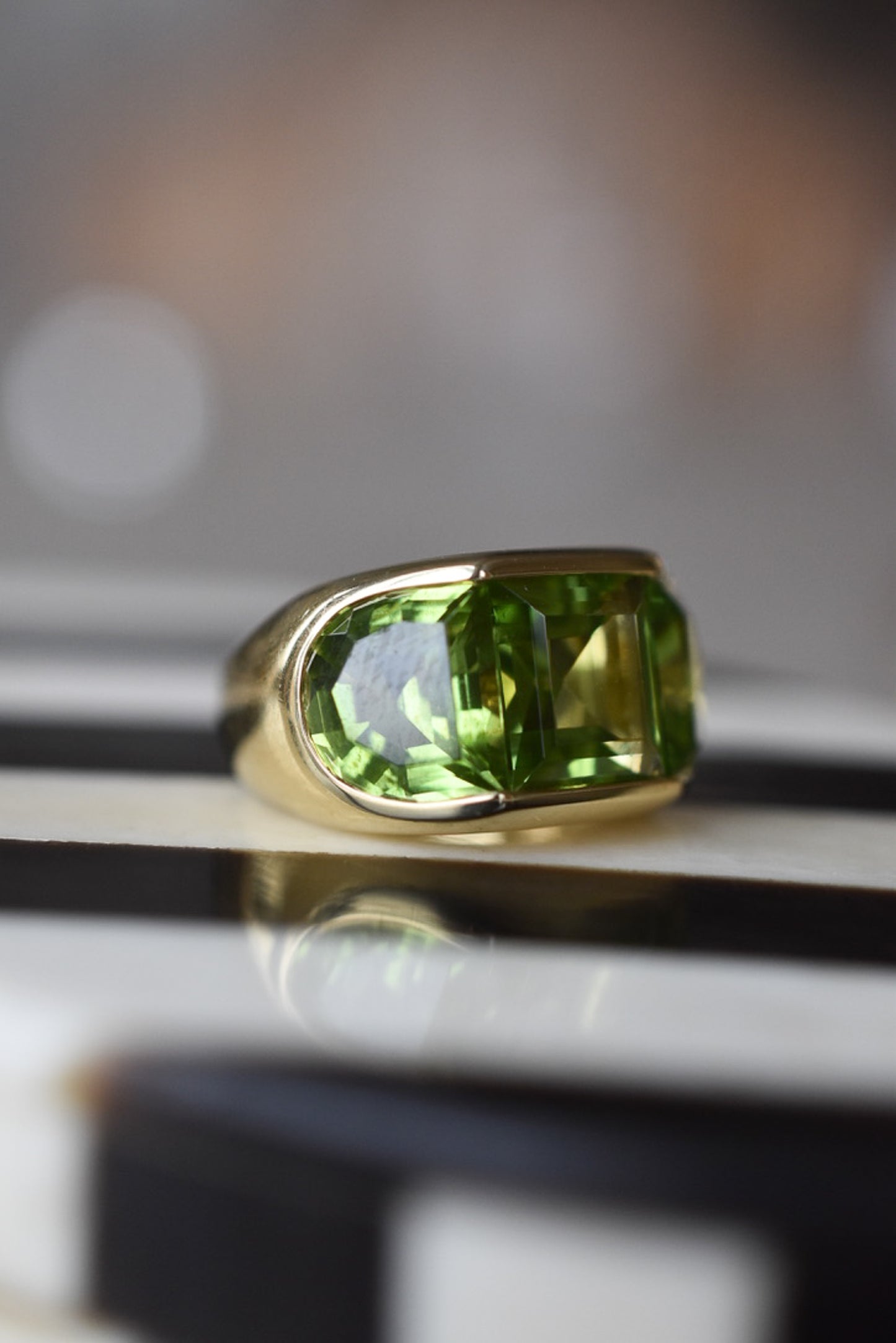 A Large Channel-set Peridot and 18K Gold Trilogy Ring