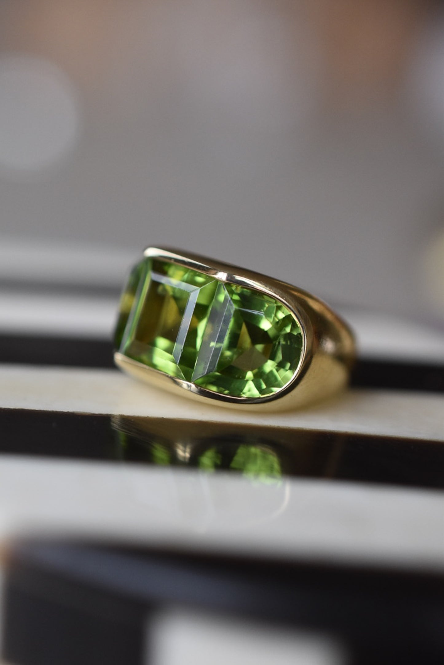 A Large Channel-set Peridot and 18K Gold Trilogy Ring