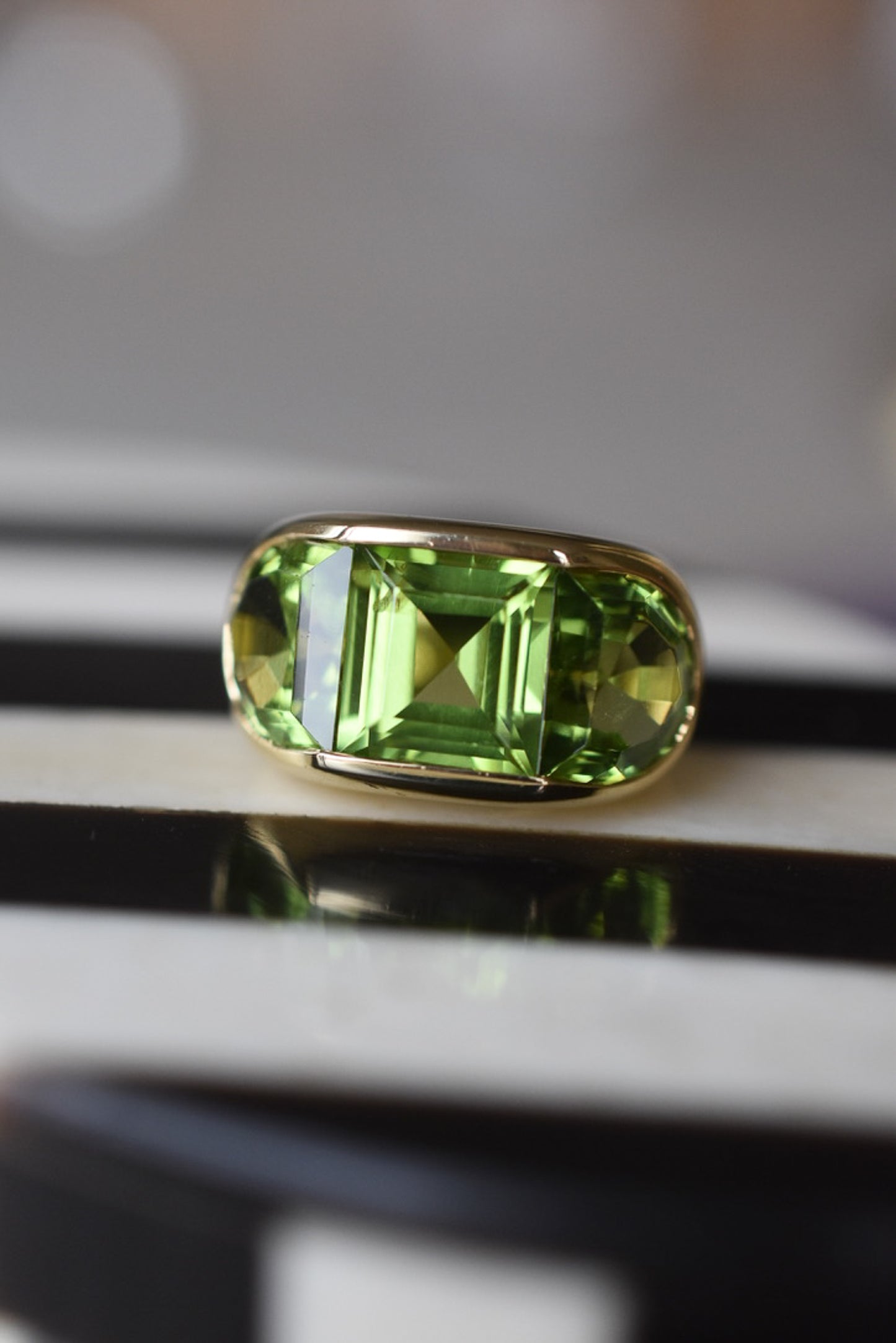 A Large Channel-set Peridot and 18K Gold Trilogy Ring