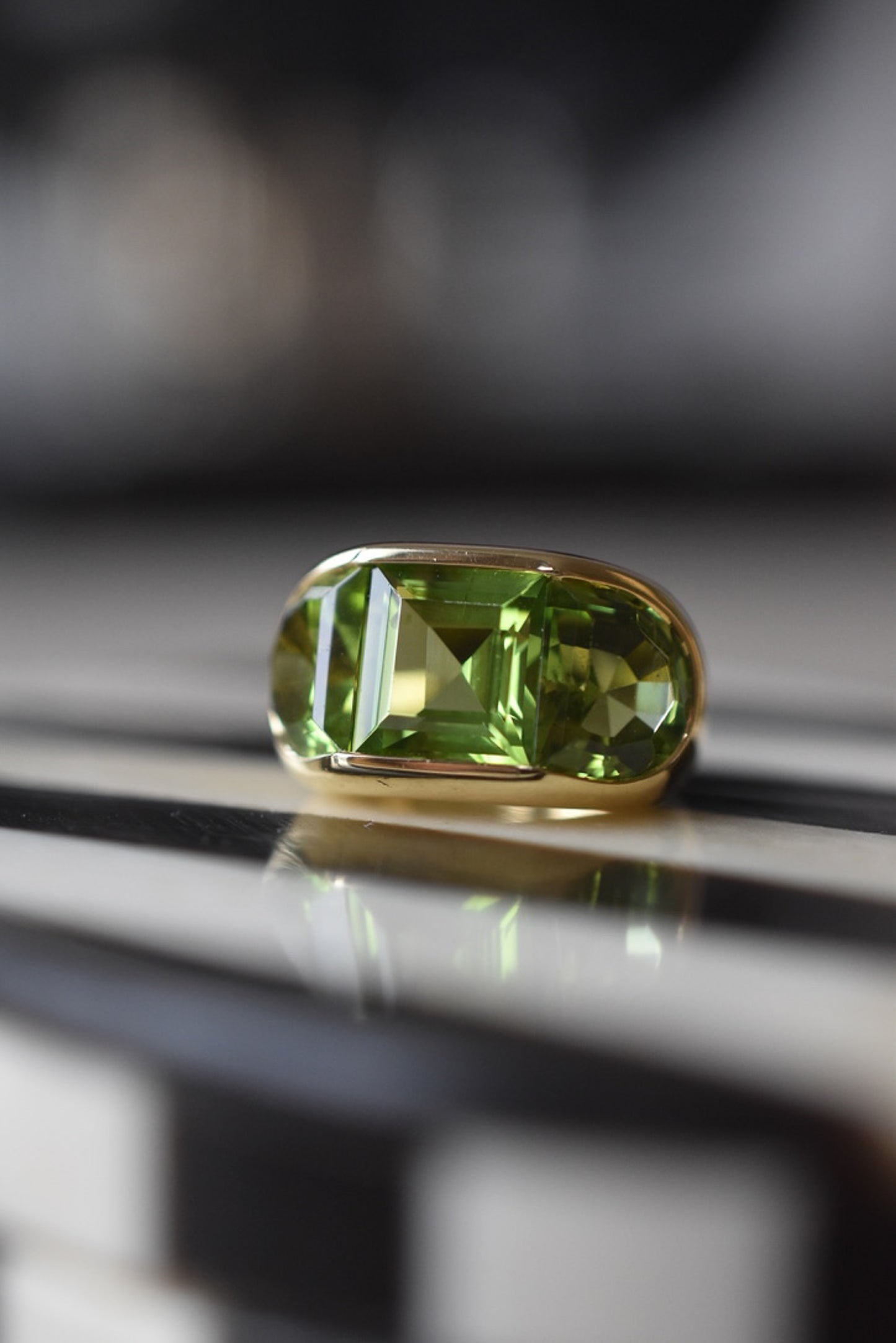 A Large Channel-set Peridot and 18K Gold Trilogy Ring